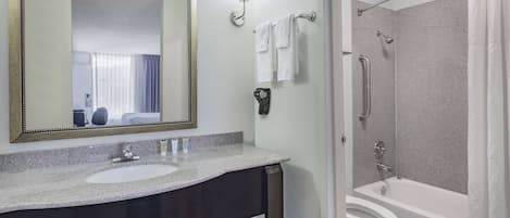 A bathroom with a sink, mirror, and shower.