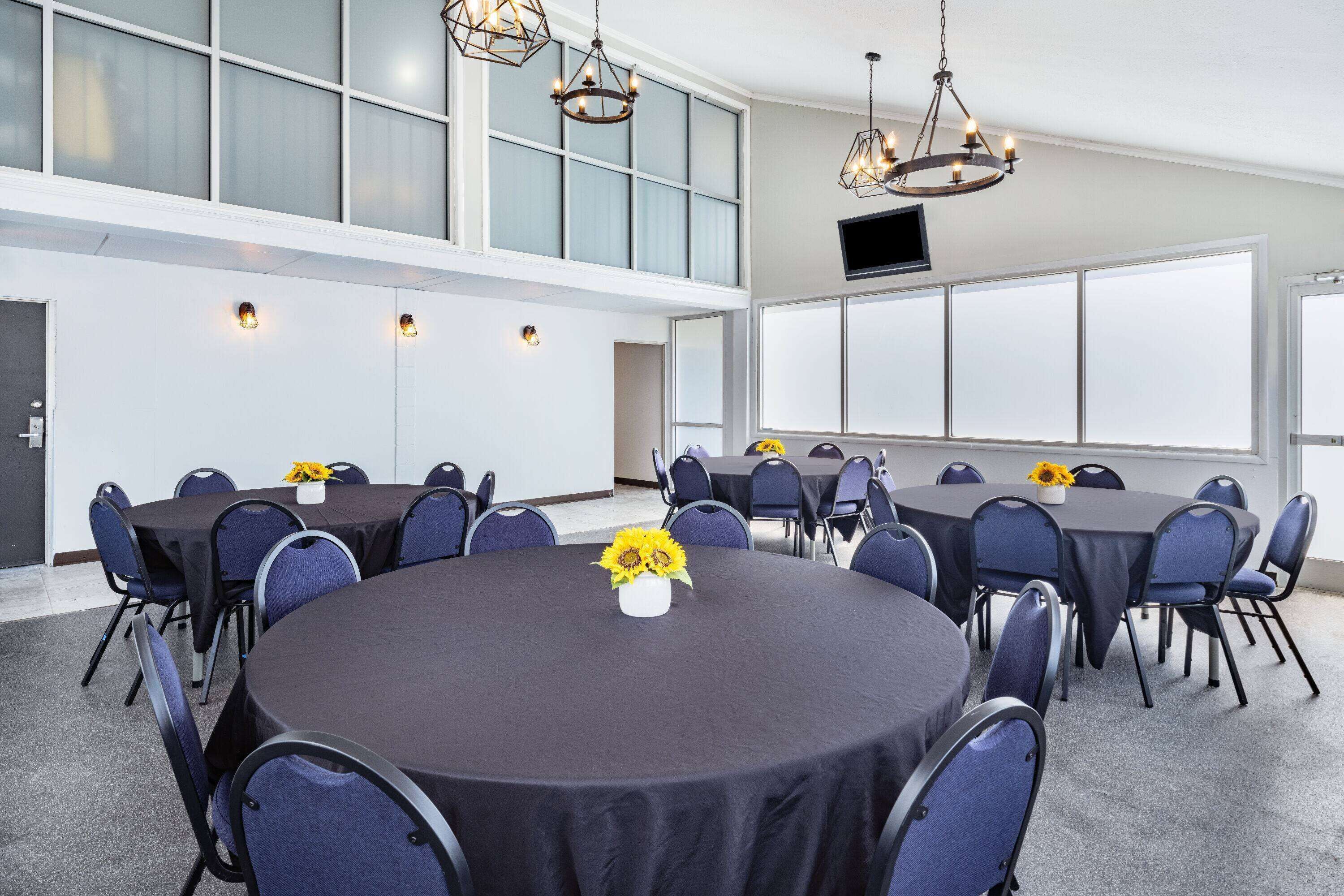 Un salón de conferencias con mesas redondas, sillas y una araña.