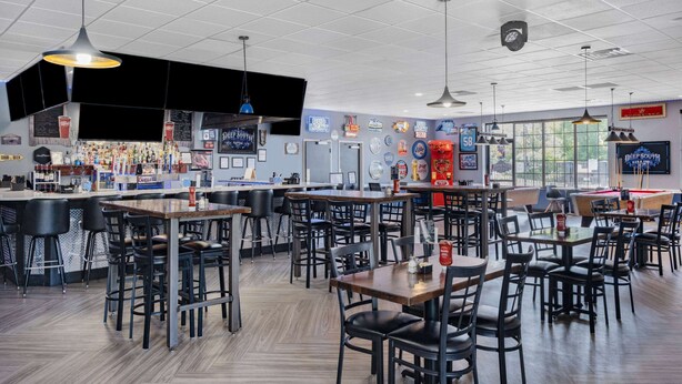 A restaurant with multiple tables and chairs, a bar area, and various beer and liquor bottles on display. - Days Inn and Suites by Wyndham Oxford (Oxford)