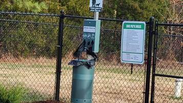 A fenced dog waste station with a trash bin and informational signs.