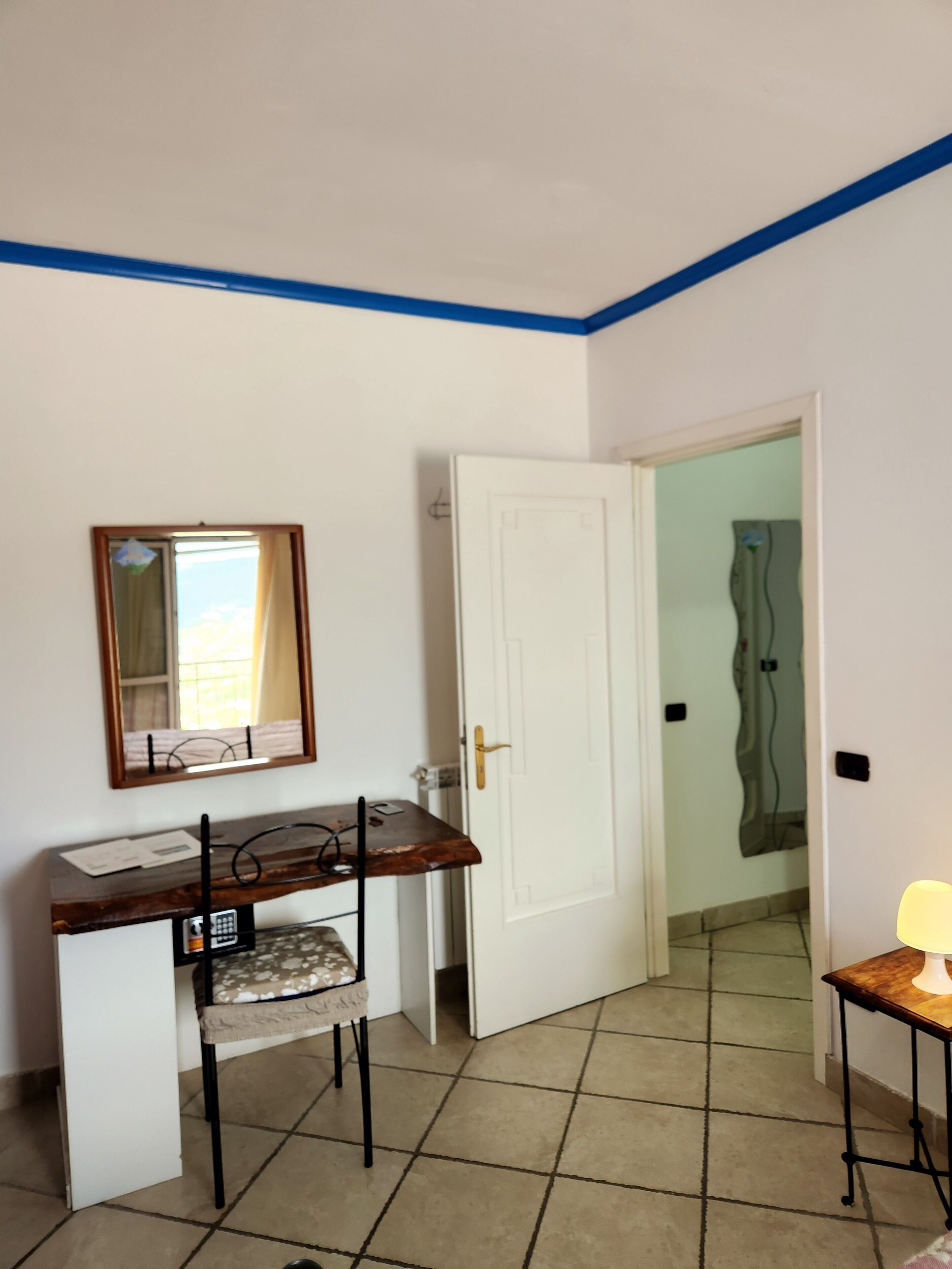 A room with a desk, chair, and a door leading to another room.