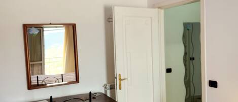 A room with a desk, chair, and a door leading to another room.