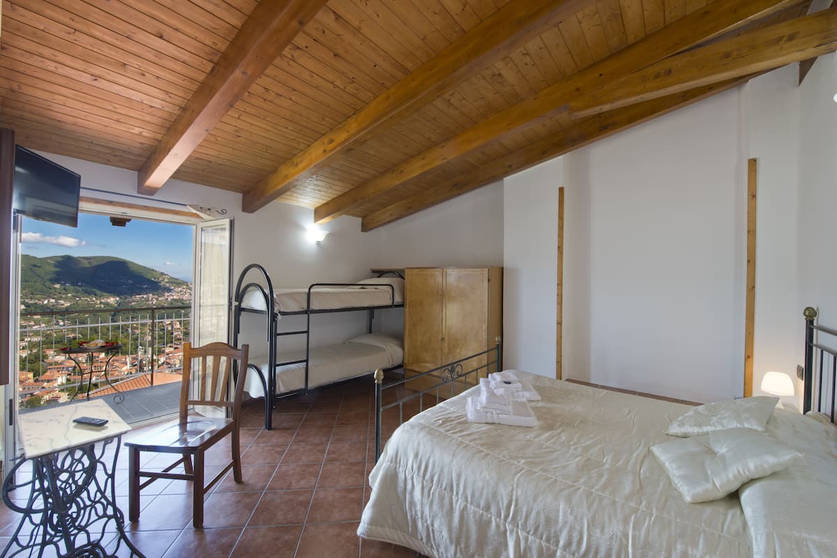 Une chambre avec un lit, une chaise, une petite table et une vue sur la ville.