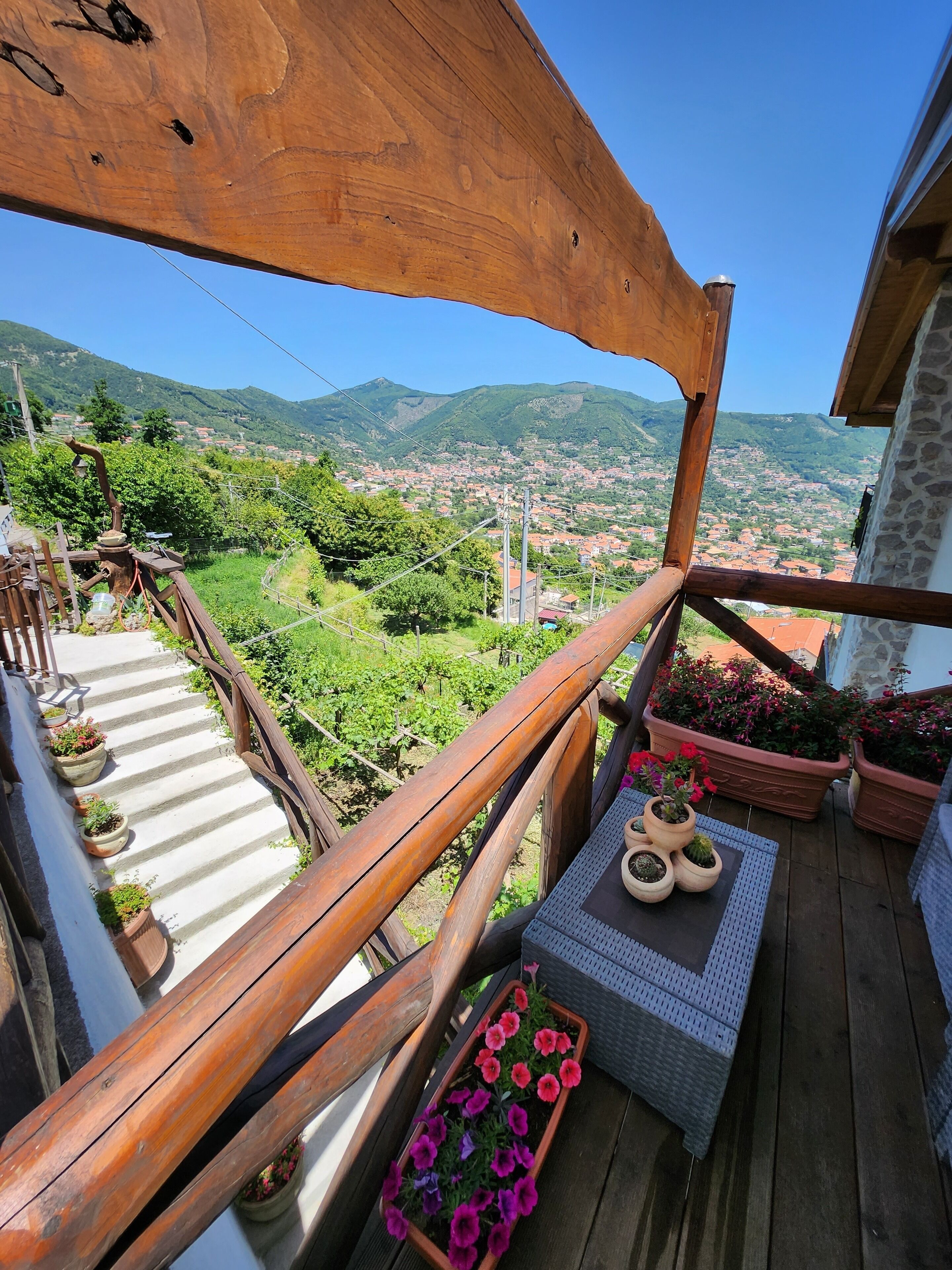 A wooden balcony with a view of a town and mountains.