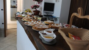 Ein Buffet mit verschiedenen Gebäcken und Desserts, einem Fernseher und einer Zimmerpflanze.