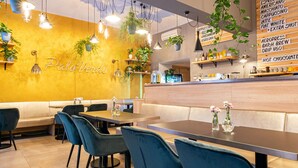 A restaurant interior with a yellow wall, blue chairs, and hanging plants. - Salvator Boutique Hotel (Prague)