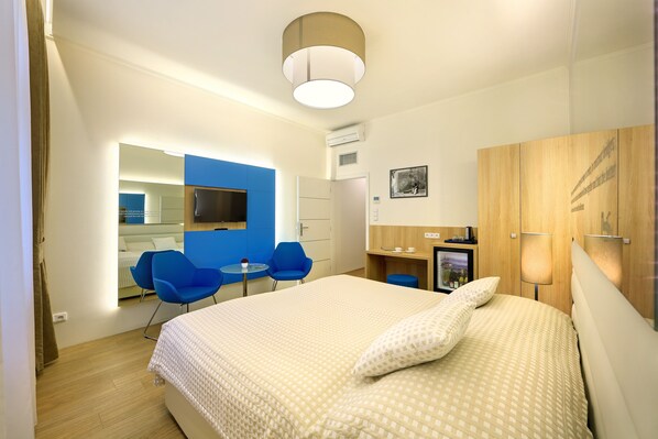 A modern hotel room with a large bed, a desk, a chair, and a television.