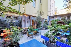 An outdoor seating area with tables and chairs, surrounded by potted plants and string lights. - Salvator Boutique Hotel (Prague)