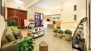 A hotel lobby with a sofa, coffee table, potted plants, a reception desk, and a bookshelf. - Salvator Boutique Hotel (Prague)