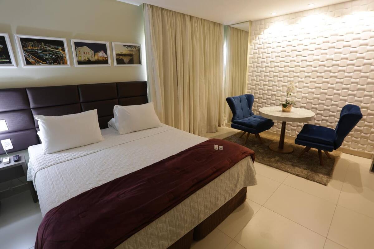Een hotelkamer met een groot bed, een ronde tafel met twee stoelen en een decoratieve wand.