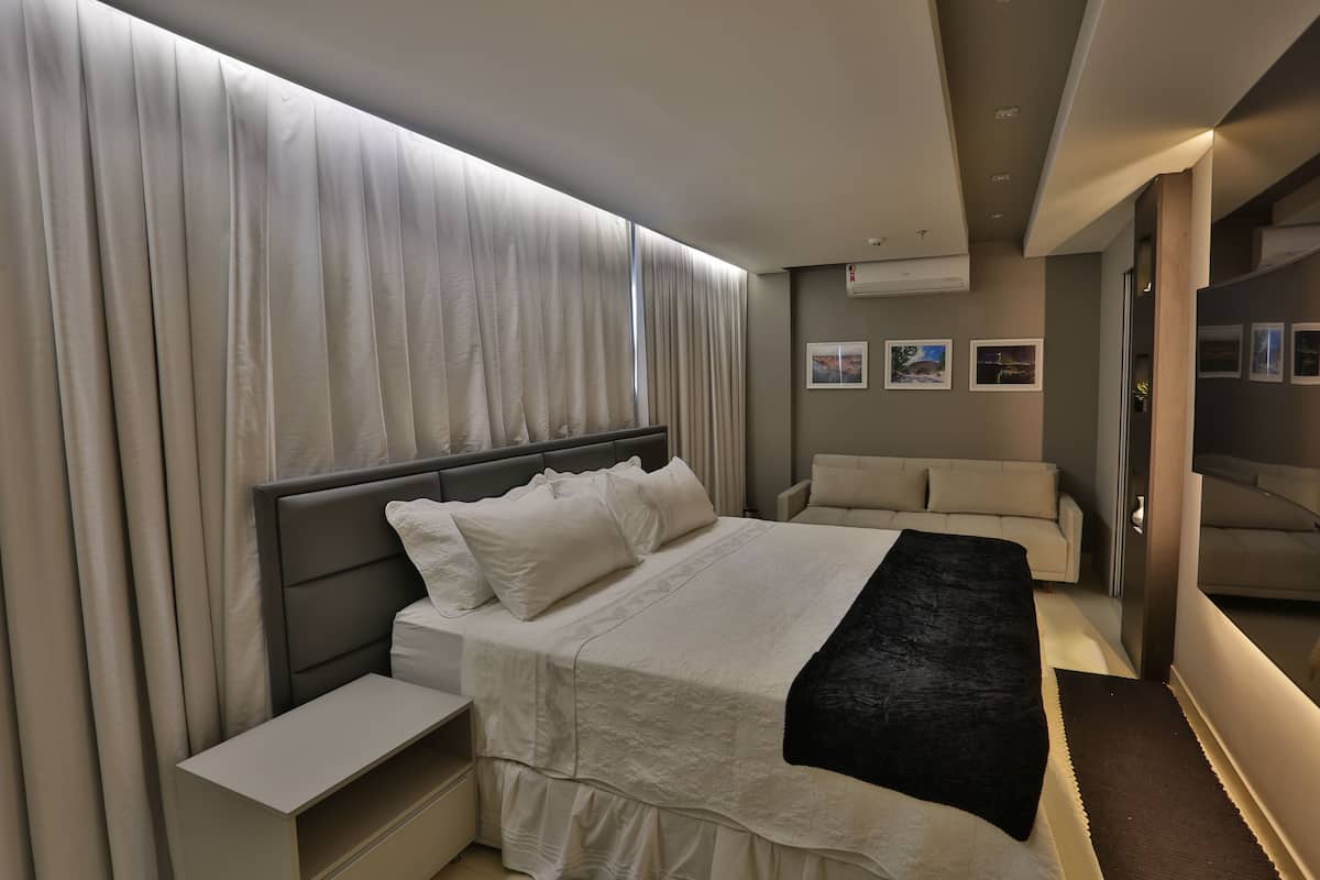 Een moderne slaapkamer met een groot bed, nachtkastjes, een bank en een inloopkast.