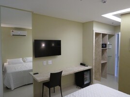 Habitación de hotel con cama, escritorio, silla, televisor y minibar.