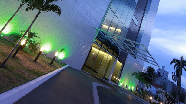 A modern hotel with a prominent sign, large windows, and a well-lit entrance area.