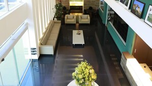 A spacious lobby with a central seating area, a reception desk, and a wall-mounted TV.