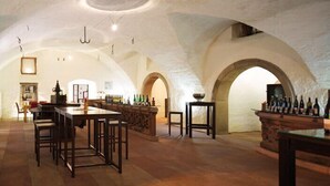 Un interior espacioso con altos techos abovedados, una zona de bar central con botellas, y un área de estar con mesas y sillas de madera.
