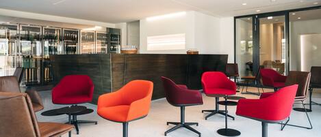 A modern lounge area with contemporary chairs and a bar area in the background.