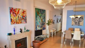 Una sala de estar moderna con chimenea, un comedor con sillas y pinturas abstractas en las paredes.