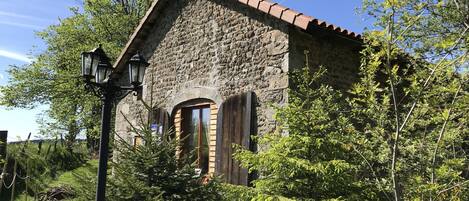A stone building with a tiled roof, a wooden door, and a street lamp.