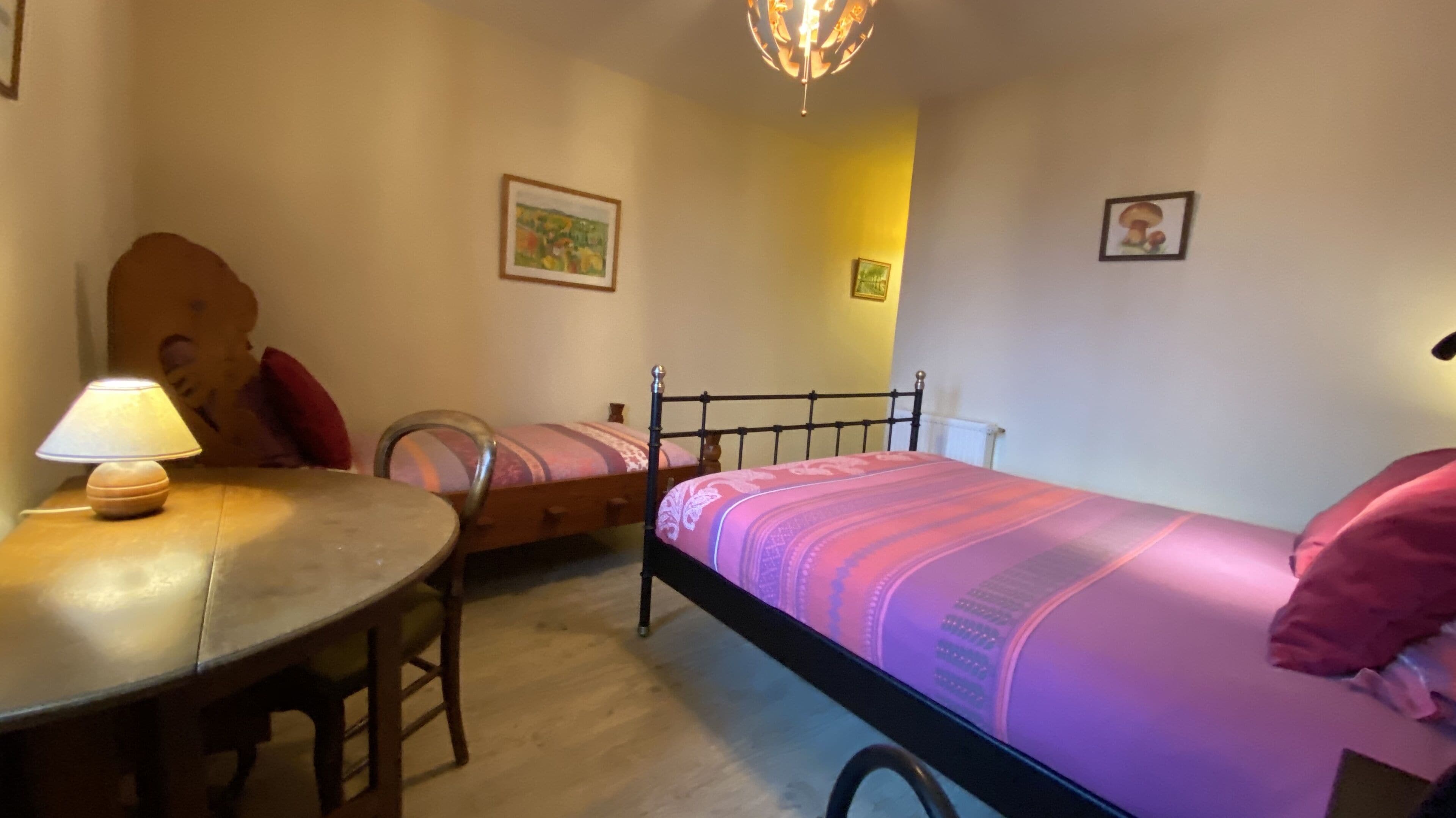 Un dormitorio con cama, una silla, una mesa y una lámpara.