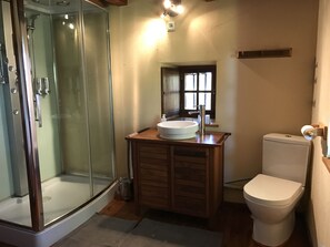 A bathroom with a glass-enclosed shower, a wooden vanity with a sink, and a toilet. - Jasserie Les Airelles (Saint-Antheme)