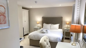 A hotel room with a large bed, two bedside tables with lamps, a chair, and a desk with a lamp. - The Rising Sun (Bristol)