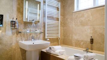 A bathroom with a sink, mirror, towel rack, and bathtub.