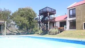 Un área de piscina con cubierta de madera y escaleras que dan a un balcón.