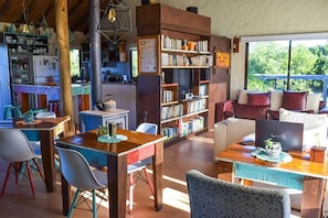 Un salon chaleureux avec une table basse en bois, une bibliothèque, un canapé et une table à manger avec des chaises.