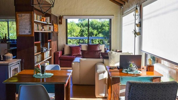 Una sala acogedora con un sofá, una mesa de comedor de madera y una estantería.