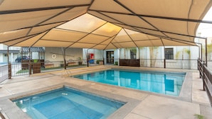 A swimming pool with a shaded area and a small hot tub. - Hotel Sntenario (Chihuahua)