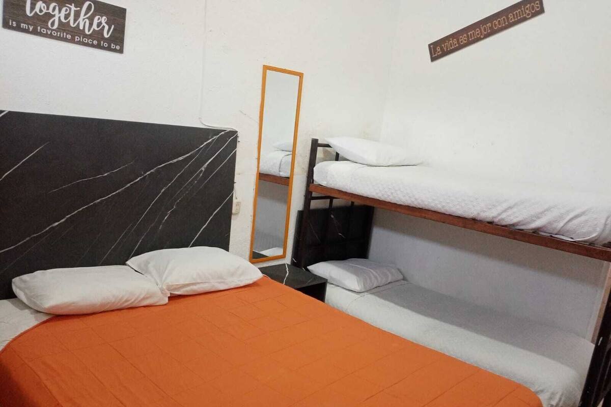 Ein Schlafsaalzimmer mit einem Bett, einem Spiegel und Etagenbetten.