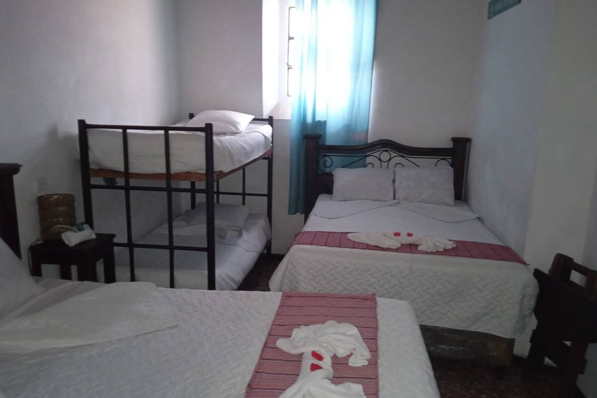 Ein Schlafsaalzimmer mit Etagenbetten, einem Einzelbett und einem kleinen Tisch.