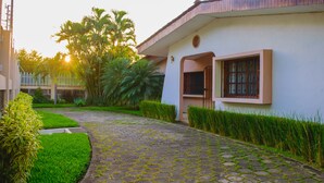 A paved pathway leading to a building with a white facade and a window with metal bars. - Hotel Fontana (Managua)