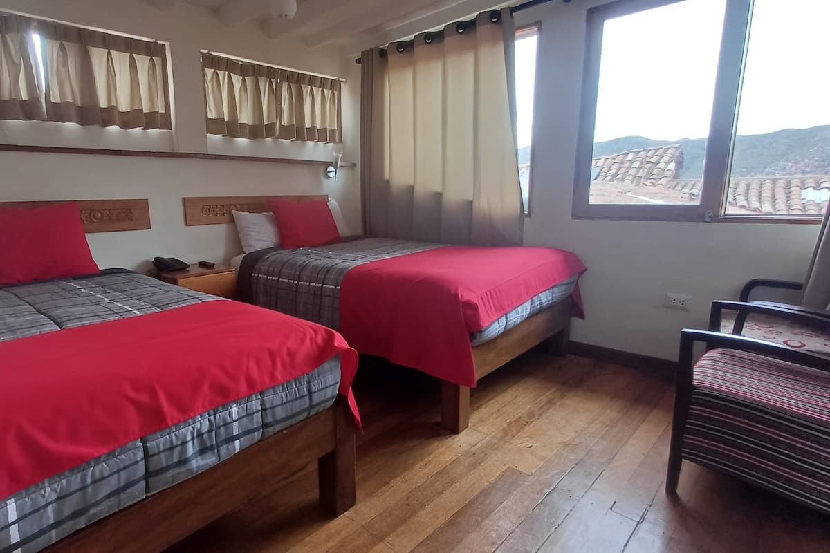 Una habitación con dos camas, cabeceros de madera y una ventana con cortinas.