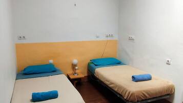 Un alojamiento pequeño, de una sola habitación, con dos camas, una mesita de noche y una lámpara colgante.