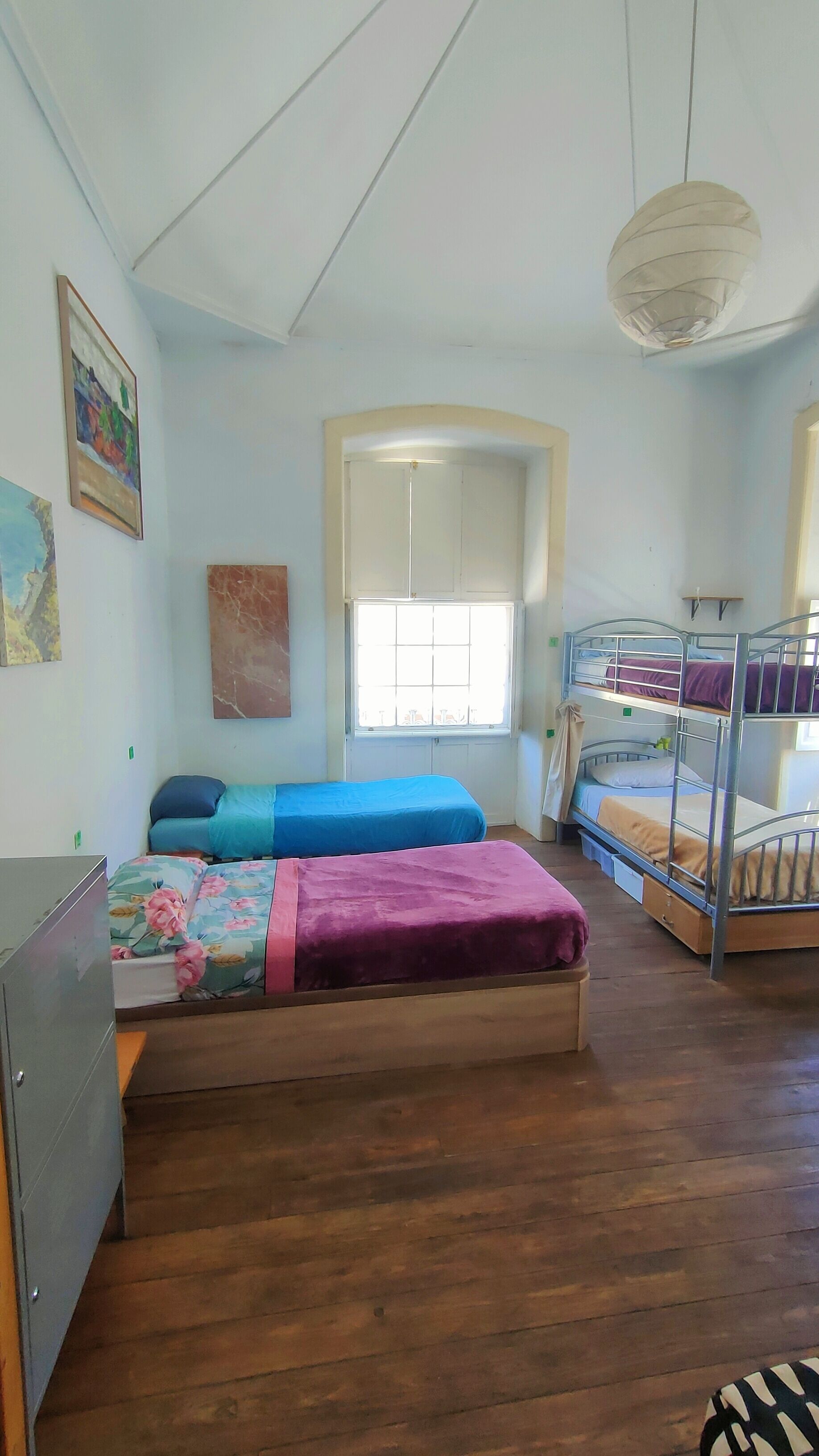Habitación tipo dormitorio con dos camas individuales, una litera, un escritorio y ventana con vistas.