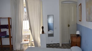 Un dormitorio con cama, una silla, cómoda de madera, un espejo y una puerta.