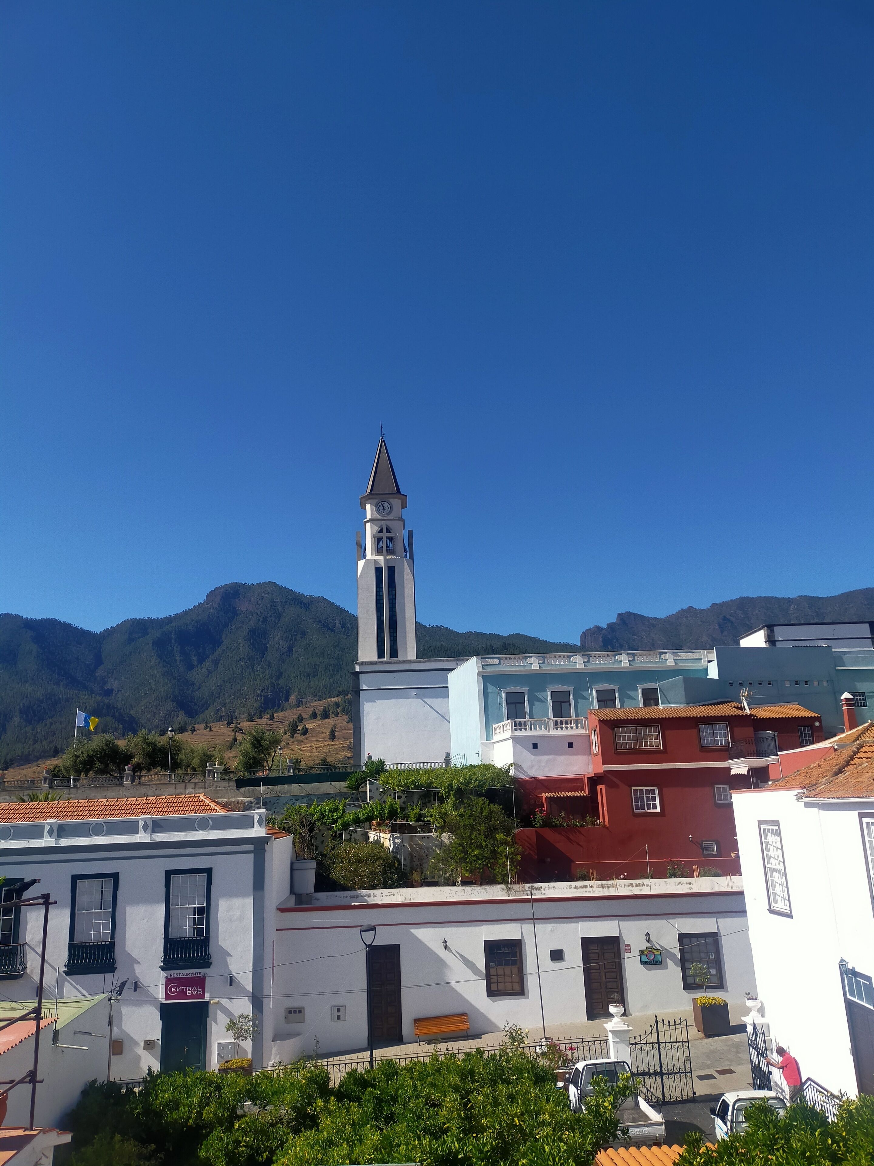 A town with a prominent church tower, a restaurant, and buildings with red and white facades.