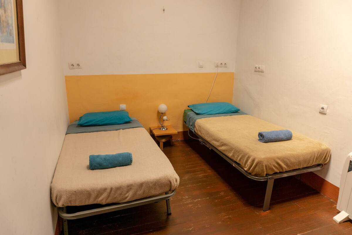 Two single beds with headboards, a bedside table with a lamp, and a radiator.