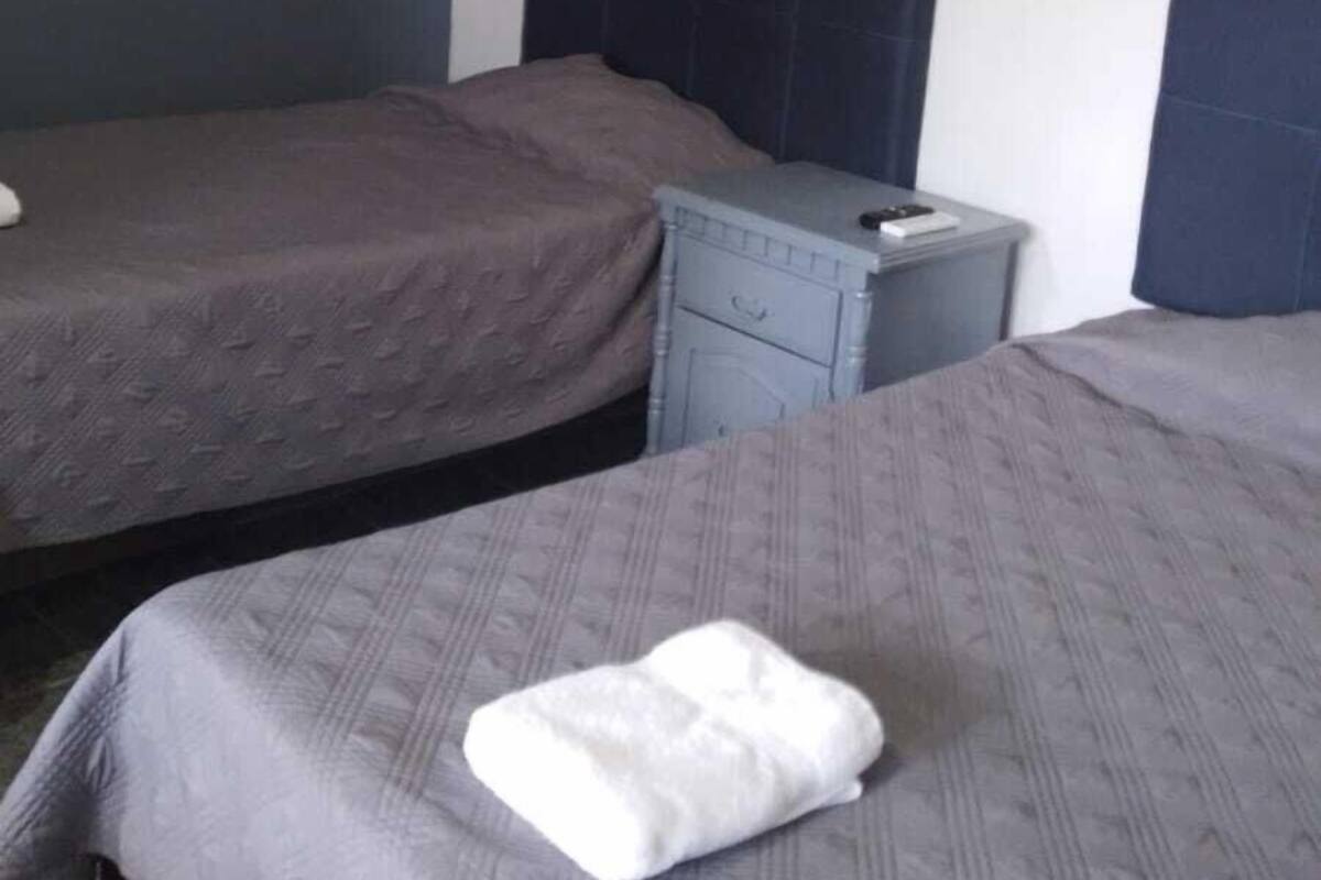 Una habitación de hotel con dos camas, una mesita de noche pequeña y una mesita auxiliar.