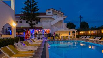 Alberca al aire libre, sombrillas en la alberca y camastros