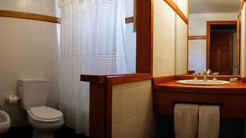 Une salle de bain équipée de toilettes, d’un bidet, d’un lavabo et d’un miroir.