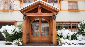 A wooden building with a snow-covered entrance and a sign displaying the number 1145. - Hosteria El Arbol Duende (San Martín de los Andes)