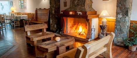 Un rincón acogedor con chimenea, bancos de madera y pared de piedra.