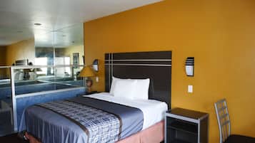 A hotel room with a bed, a nightstand, a lamp, and a mirror.