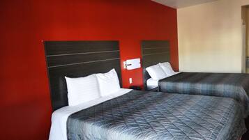 A hotel room with two beds, each with a headboard and white pillows.