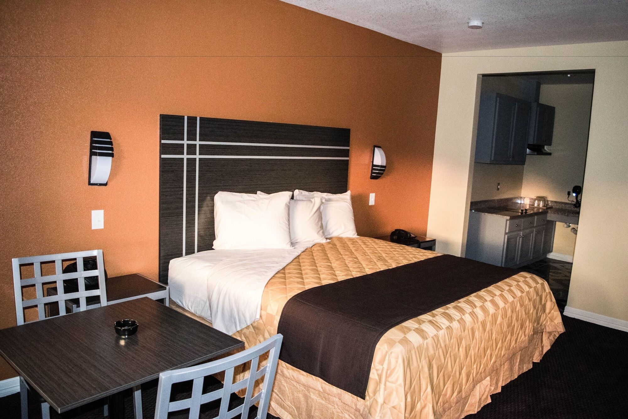 A hotel room with a bed, a desk, and a kitchenette.