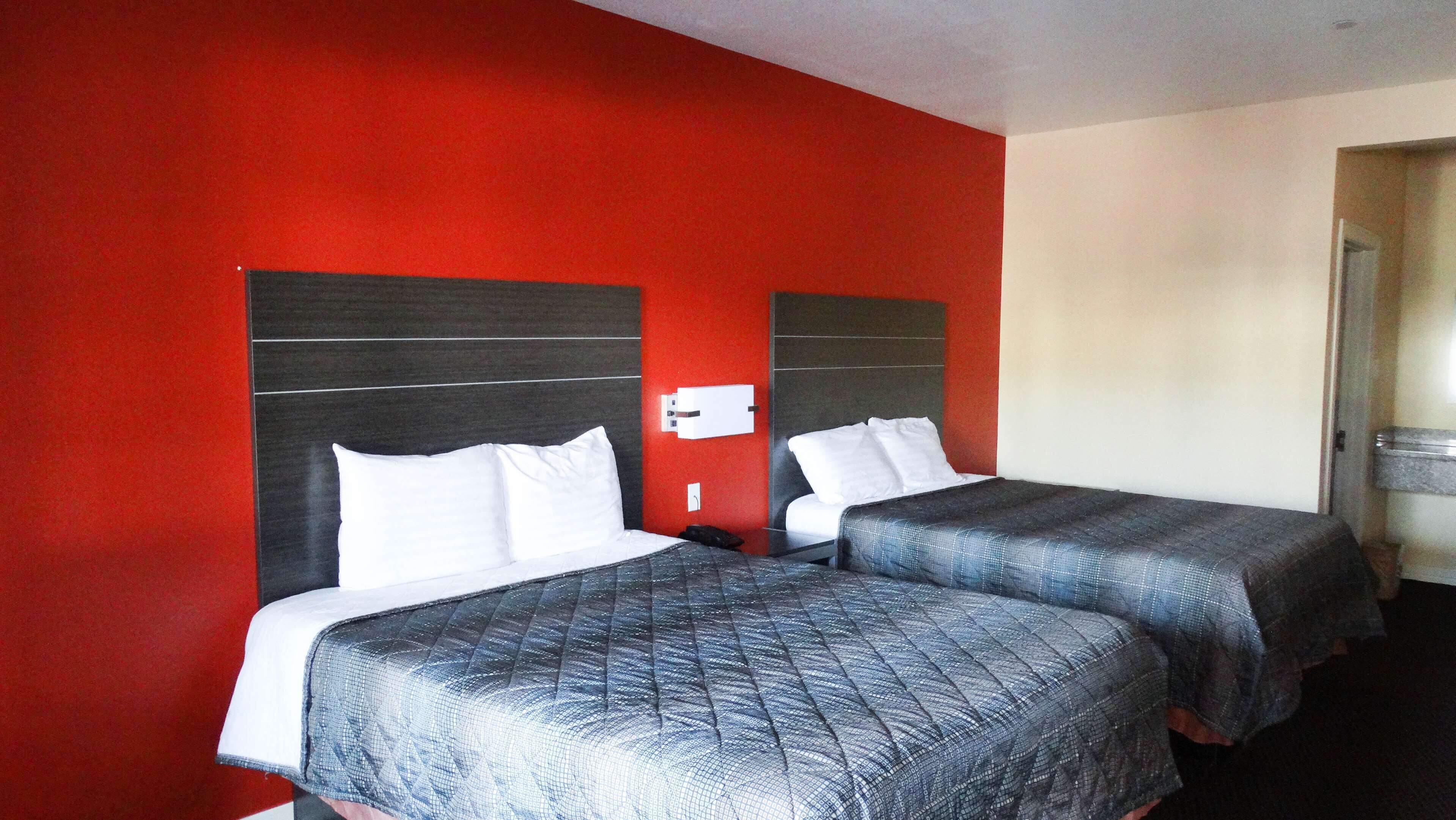 A hotel room with two beds, red walls, and a white door.
