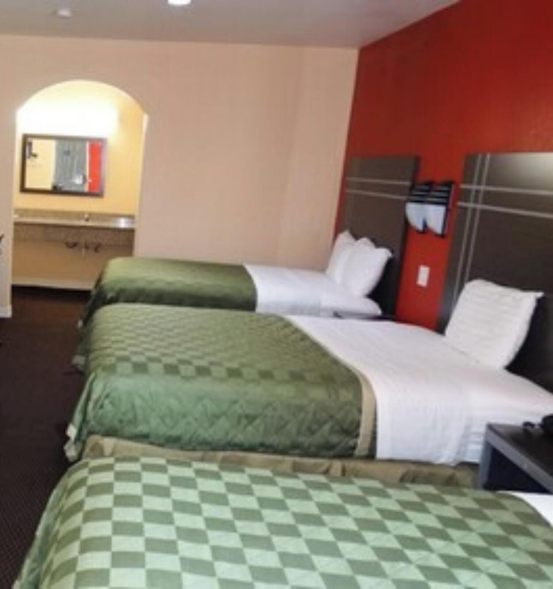 A hotel room with two beds, a small bathroom, and a mirror.