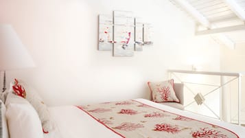 Un dormitorio con cama, mesita de noche, lámpara y ventana.